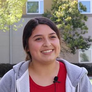 student sitting outside, smiling at camera